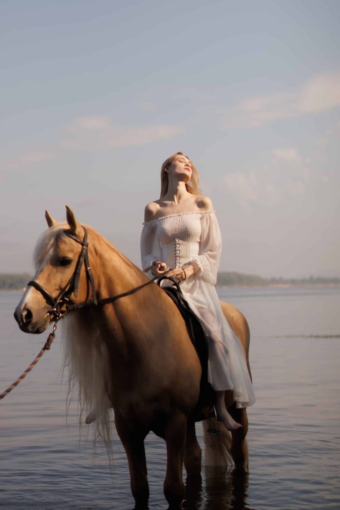 Woman riding medievil horses on beach