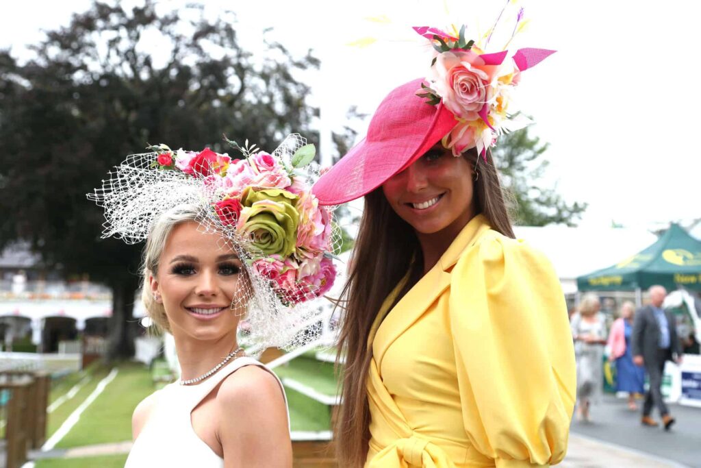 Two well dressed ladies wearing decorative hats at York Races